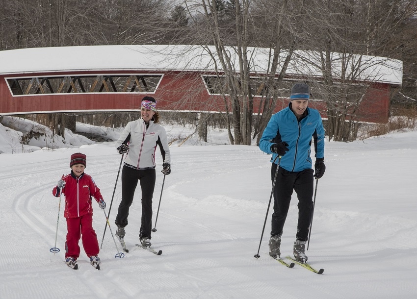 Happy Family skiing at Jackson XC covered bridge in background