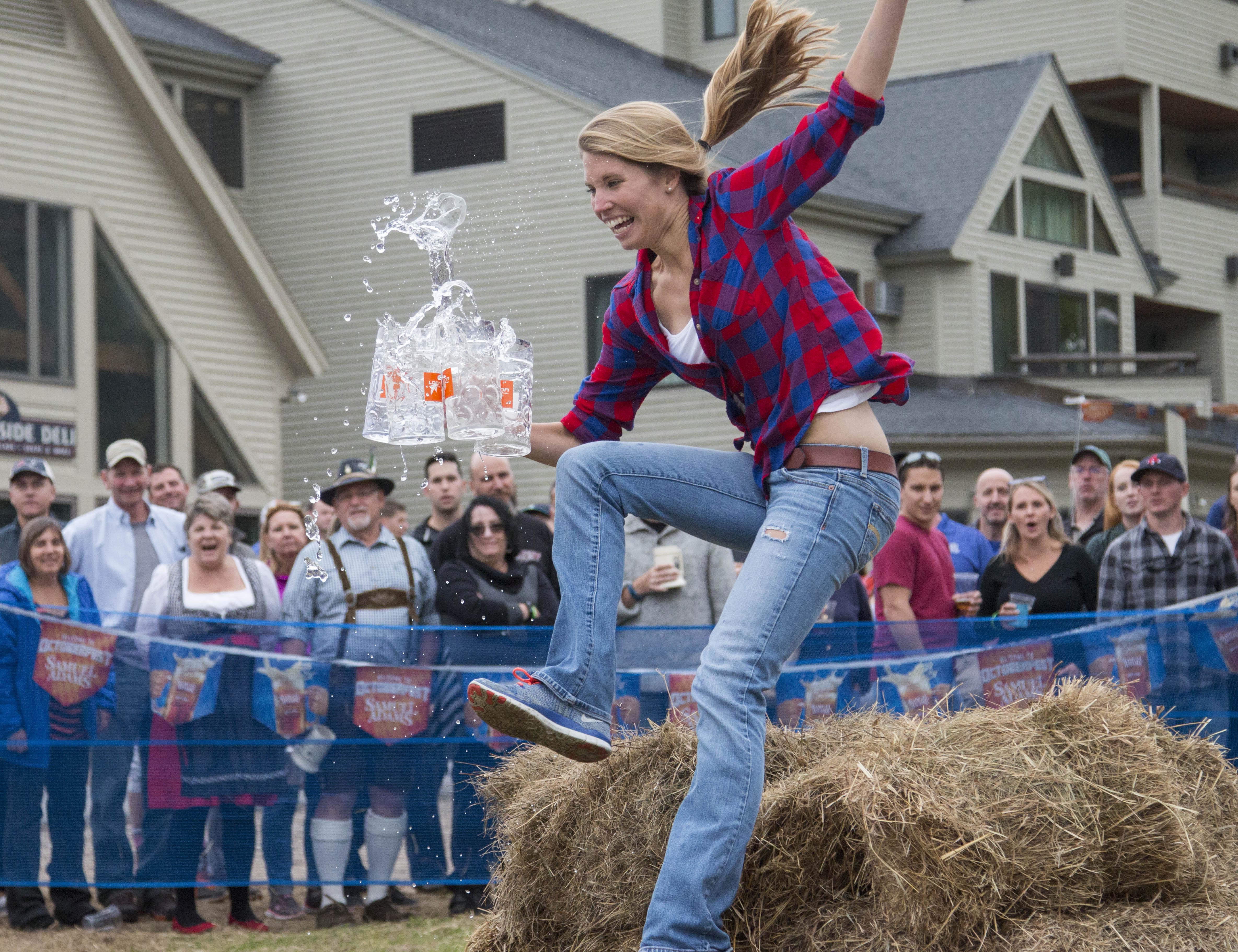 woman carrying beer mugs and jumping hay bales
