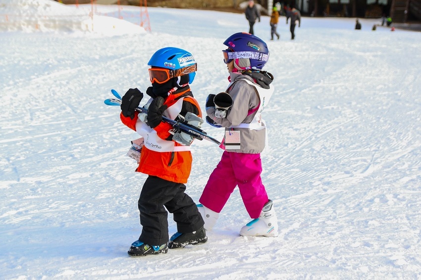 Kids carrying skiis