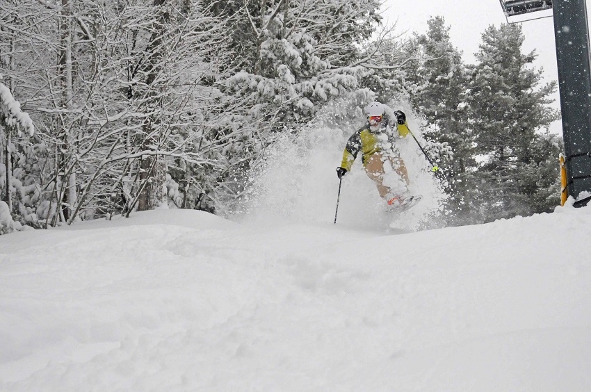 Skier jump turn in powder yellow jacket