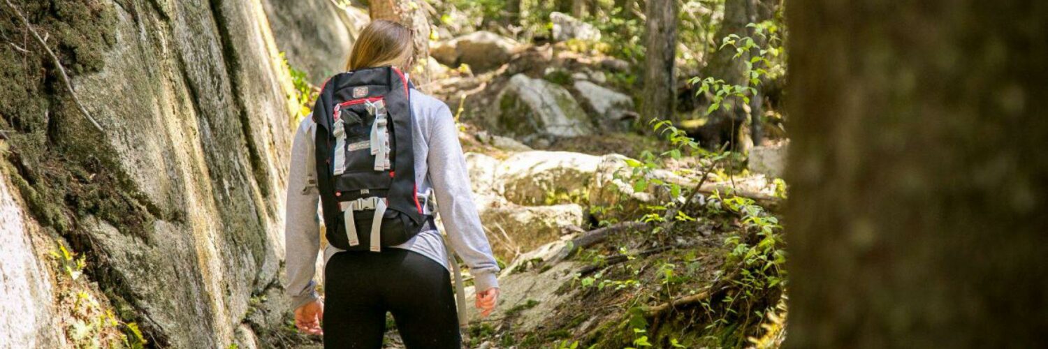 one woman with backpack hiking over rocks