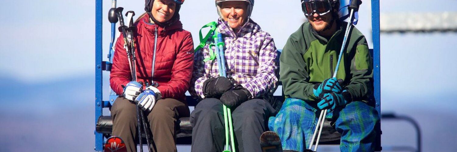 Three adults on chair lift