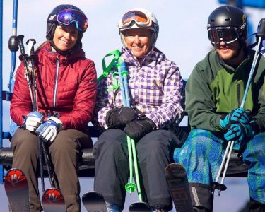 Three adults on chair lift