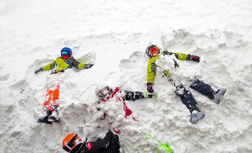 making snow angels in ski boots and helmets
